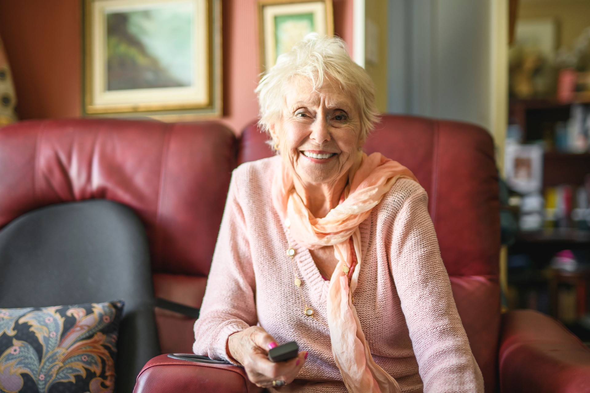 Beautiful senior woman listening TV in the living room